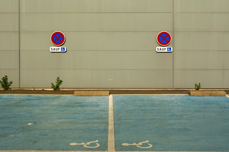 A photograph depicting a designated parking area for home relocation and furniture transport near a building with a grey wall. The parking spaces are marked with light blue paint, including one labell