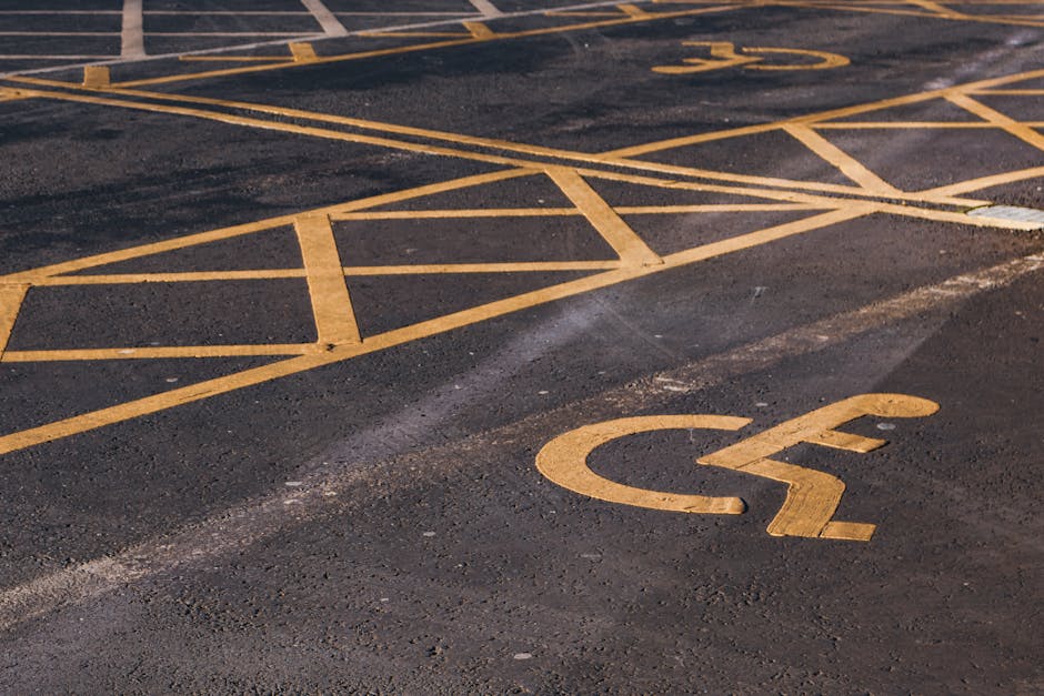 A photograph depicting a designated parking area for home relocation and furniture transport near a building with a grey wall. The parking spaces are marked with light blue paint, including one labell