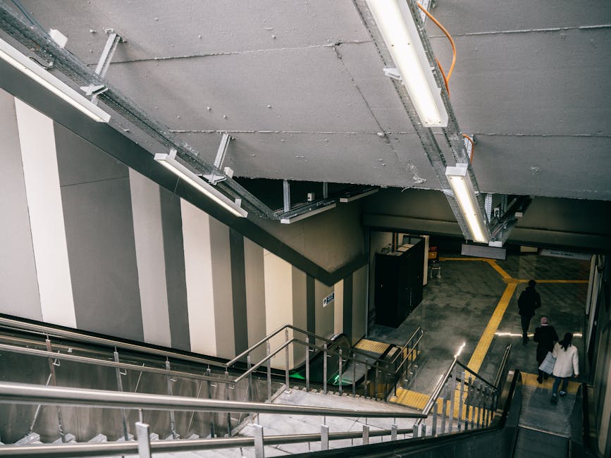 An indoor stairway leading up to an exit at Wennington station, with a yellow and black sign overhead displaying the word 'Lối ra' and the English translation 'Exit' along with an upward-pointing ar